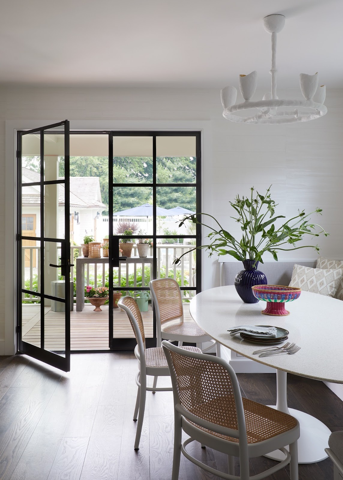 Modern coastal home dining room with black steel-framed doors opening to outdoor deck showing architectural approach to seaside living and indoor-outdoor flow
